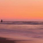 Man surf fishing at sunset