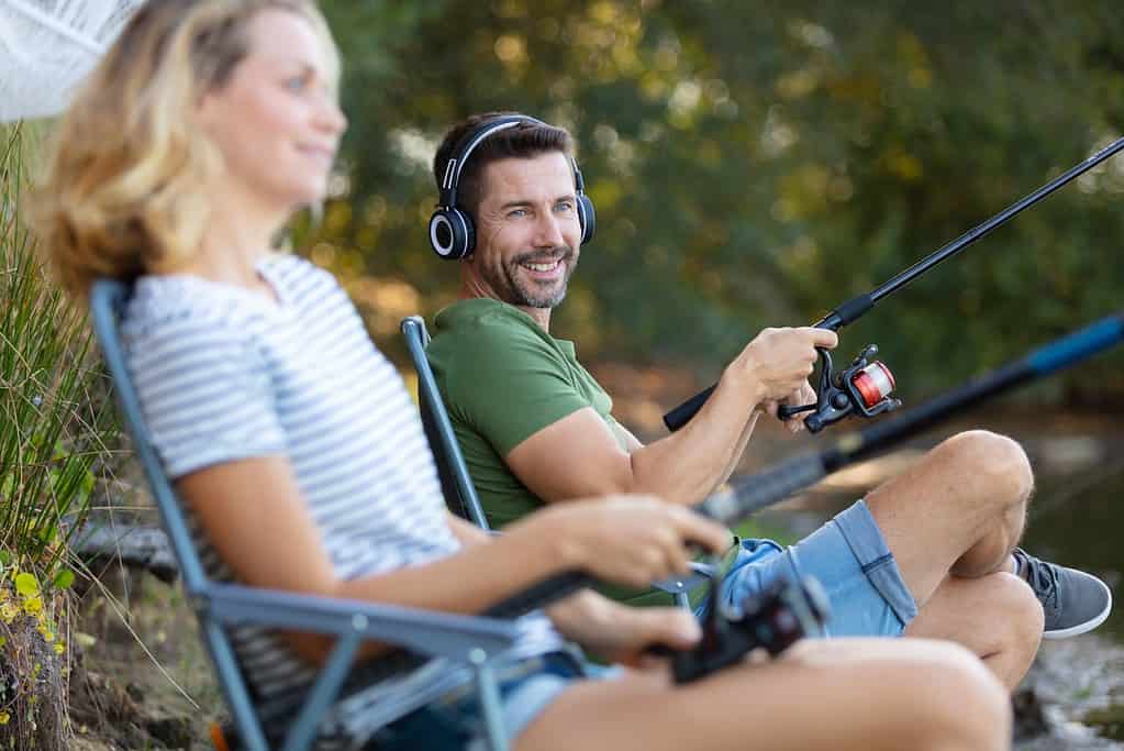 man on headphones fishing with lady in chair
