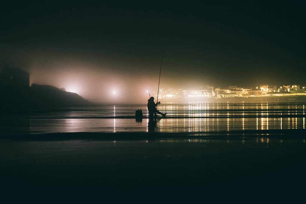 man surf fishing at night