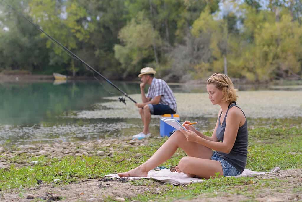 woman reading while man fishes