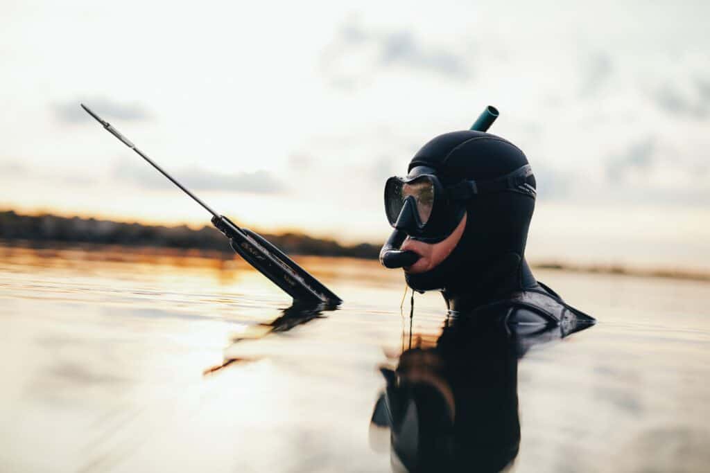 man spearfishing head out of water